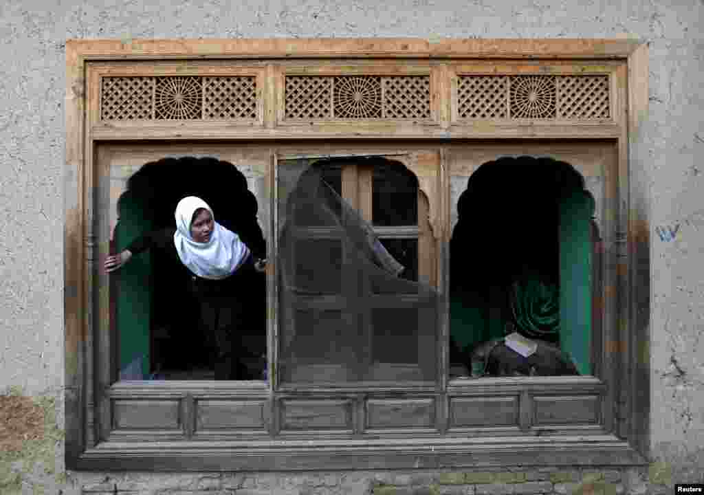 An Afghan girl looks out of a damaged window of a shrine after a suicide attack in Kabul on March 25. (Reuters/​Mohammad Ismail)