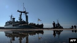 Marinarii ucraineni de la vasul Slavutici se uită lmilitarii ruși care patrulează în portul Sevastopol, 5 martie 2014.