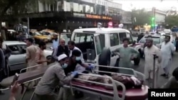 People carrying an injured person to a hospital after an attack at Kabul airport on August 26, 2021. 