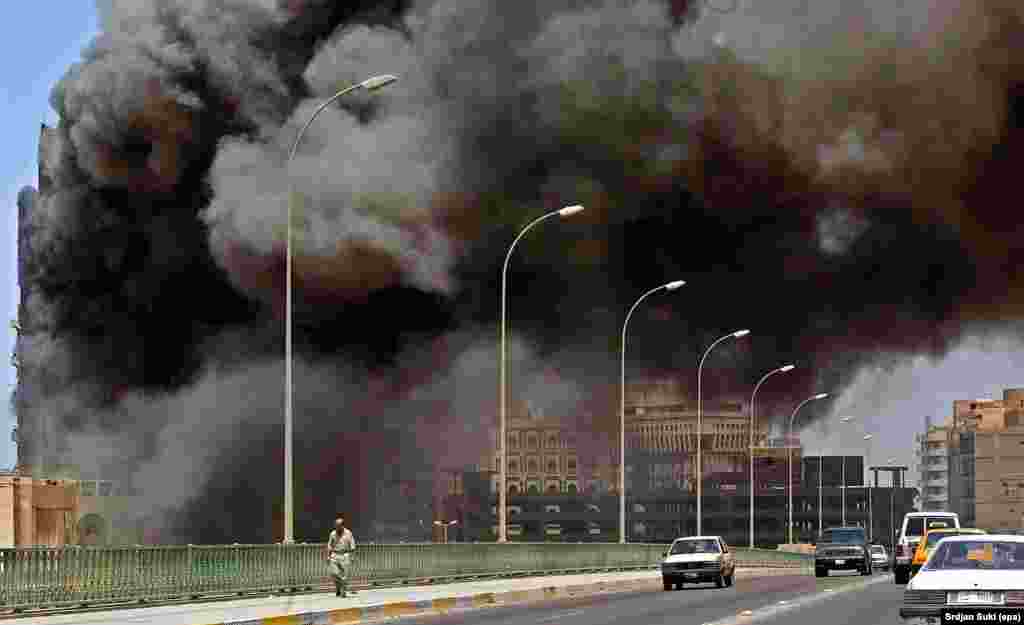 A building in central Baghdad burns as Iraqis pass by apparently unconcerned in May 2003, two months after the 2003 U.S.-led invasion of Iraq.