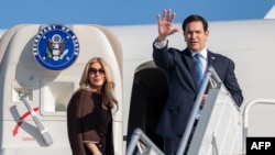 US Secretary of State Marco Rubio (right) waves next to his wife, Jeanette Dousdebes Rubio, as they board a plane to leave Samarkand on October 20. 