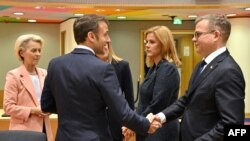 A francia elnök és a finn kormányfő kézfogása az Európai Tanács ülésén Brüsszelben 2023. december 14-én