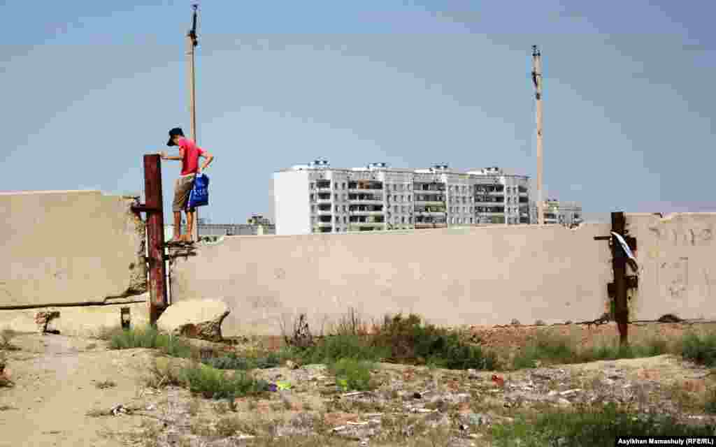 Akay residents jumping over the concrete wall to get into Baikonur. In this illegal way people avoid the long lines and bureaucracy needed to get a special entry pass. The Russian administration fines people caught going over the wall.