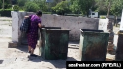 A woman looks in garbage cans for food in Ashgabat.