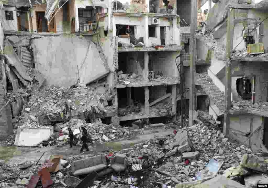 Men walk along a street lined with debris and damaged buildings in Homs, Syria. (Reuters/Yazan Homsy)