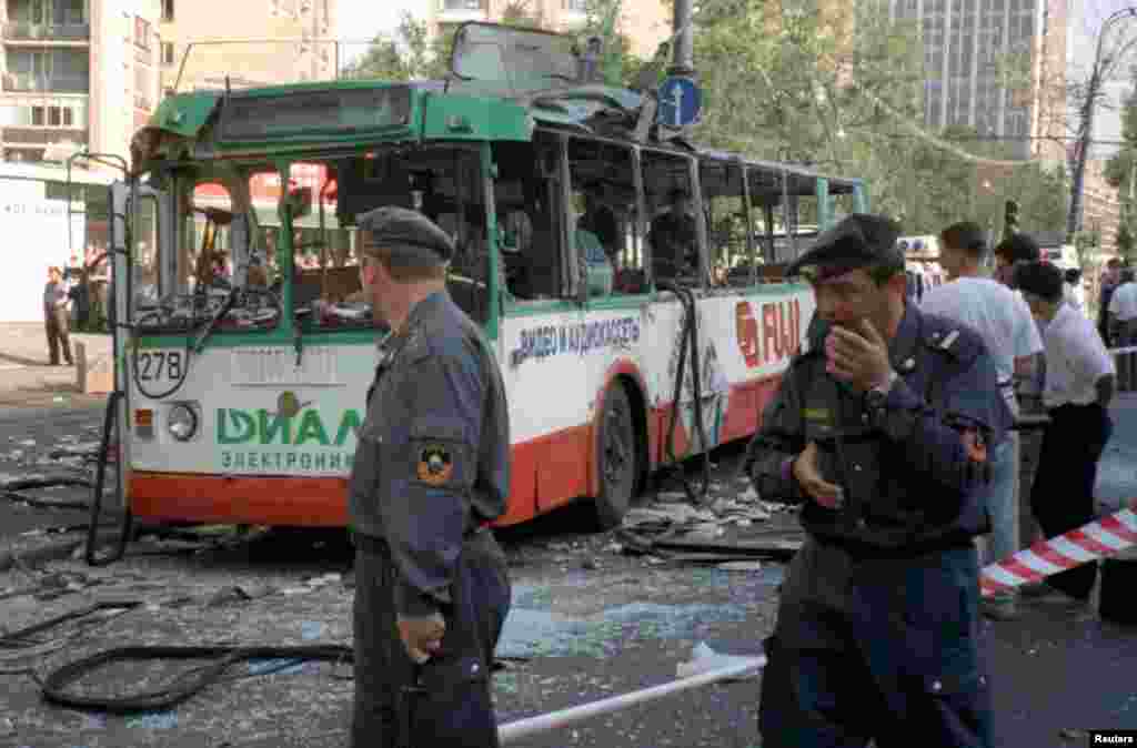 A Russian militiaman passes a security cordon as experts work inside a blown-up trolleybus on Prospekt Mira (Peace Avenue) in Moscow, July 12, 1996. A bomb left in a bag ripped through the vehicle in the morning rush hour.
