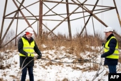 Енергийният министър на Латвия Каспарс Мелнис и Роландс Ирклис, директор на държавния системен оператор за пренос на електроенергия AST, позират с прекъснат кабел по време на прекъсването на основния електропровод между Латвия и Русия.