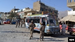 Pakistani security officials inspect the site of an incident were unknown assailants opened fire on a bus in Hazara Ganji area of Quetta on 23 October 2014.