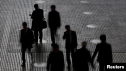 eople walk at an office building at a business district