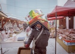 Un muncitor cară cutii în cea mai friguroasă piață din lume, unde carnea și peștele înghețat se vând fără a fi nevoie de frigidere.