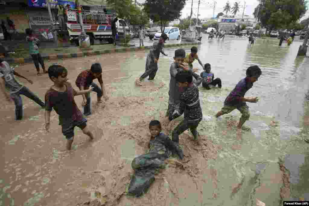 Pakistani boys play in a flooded street after heavy rainfall in Karachi. (AP/Fareed Khan)