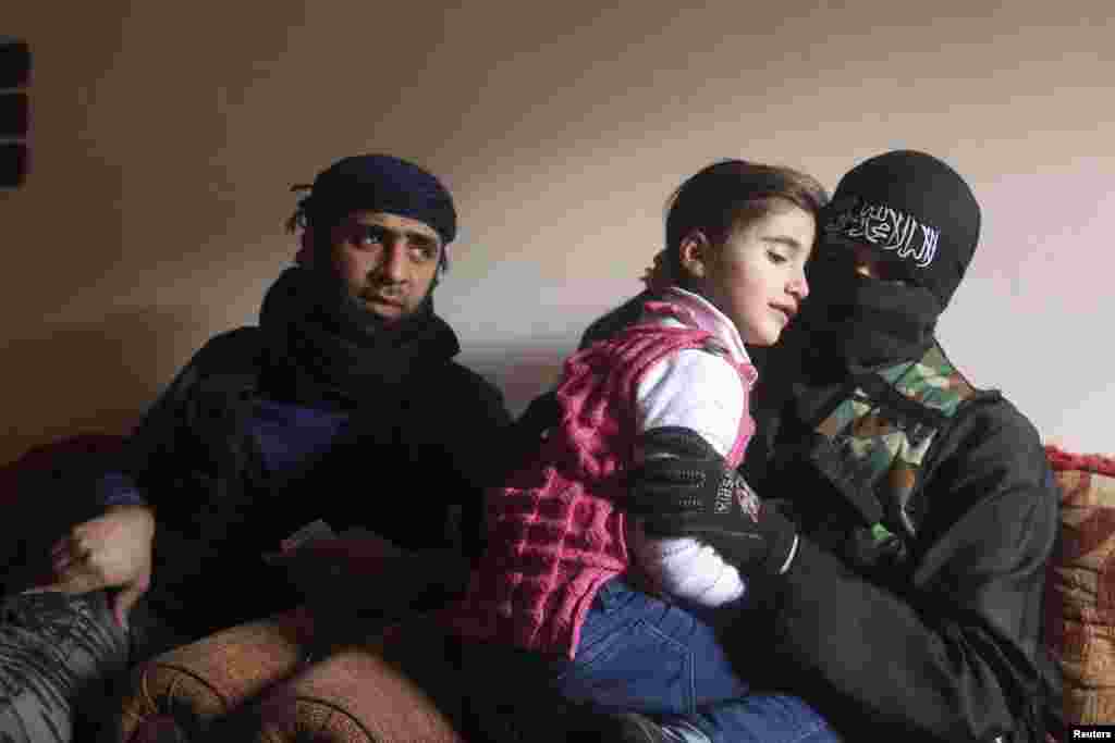 Um Jaafar, a woman fighter in the Free Syrian Army, sits with her husband, Abu Jaafar, a Sawt al-Haq (Voice of Rights) battalion commander, and their daughter Faten at their home in Aleppo. Um Jaafar was a hairdresser before the revolution. (Reuters/Muzaffar Salman)