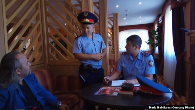 Полицейские составляют протокол в отношении украинского журналиста Александра Гороховского (слева) во время встречи в рамках проекта "Школа журналистики" в гостинице Уральска, 15 сентября 2018 года.