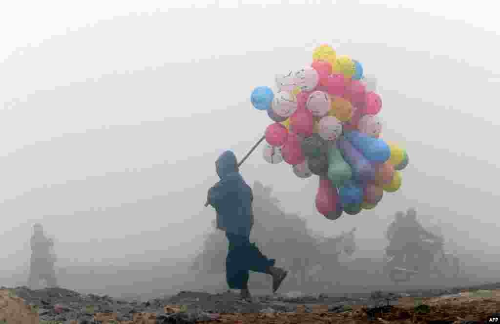 A balloon vendor sells his wares on a cold and foggy morning in Lahore, Pakistan. (AFP/Arif Ali)