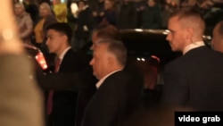 Orbán Viktor Tbilisziben, háttérben az őt kifütyülő ellentüntetők