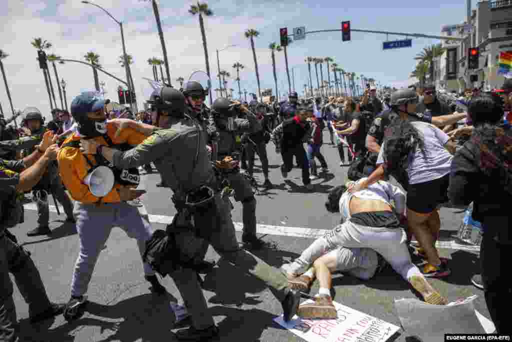 Poliția americană intervine ca să pună capăt ciocnirilor dintre protestatari și susținători ai președintelui Donald Trump, în timpul unei manifestații din Huntington Beach, California, 6 iunie 2020.