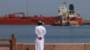 A man stands by the waterfront as a vessel sits at anchor at Sultan Qaboos Port in Muscat.