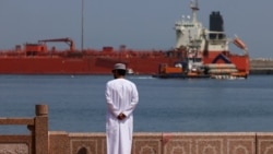 A man stands by the waterfront as a vessel sits at anchor at Sultan Qaboos Port in Muscat.