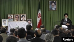 Iranian Supreme Leader Ayatollah Ali Khamenei (right) attends a meeting in February in Tehran with Iranian nuclear scientists and managers as portraits of recently slain Iranian scientists are displayed.