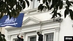 Четверо мужчин на балконе посольства Ирана в Лондоне размахивают флагами, устраивая протест против политики Тегерана. 9 марта 2018 года.