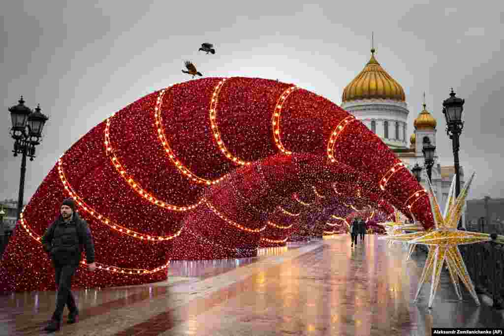 People walk on a Moscow bridge decorated for Christmas and New Year celebrations with the Christ the Savior Cathedral in the background. (AP/Alexander Zemlianichenko)