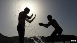 آرشیف - در یک روز گرم تابستان در کابل یک دوست، بالای دوست دیگر آب می پاشد. 