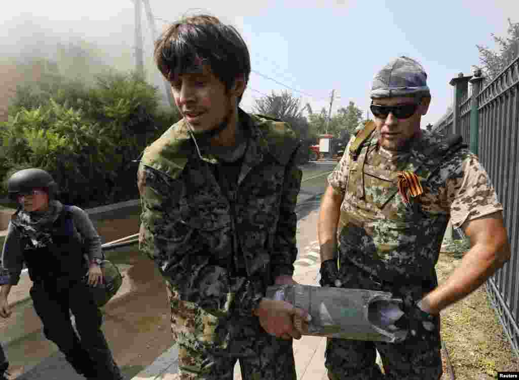 Pro-Russian separatists carry part of an exploded shell shortly after a shelling in Donetsk, Ukraine, on August 14. (Reuters/Sergei Karpukhin)