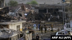 Pakistani security officials investigate the site of a bombing in Lahore on August 7.