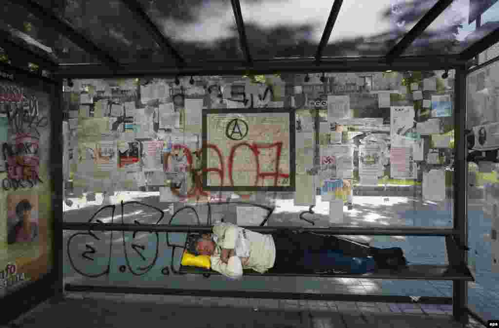 A man sleeps at a bus stop near Independence Square in downtown Kyiv. (epa/Yuri Kochetkov)