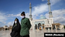 An Iranian couple wearing face masks to protect against the coronavirus walk in the holy city of Qom. 