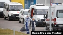 A medical specialist wearing protective gear accompanies a man outside a hospital for patients infected with the coronavirus disease on the outskirts of Moscow on October 7.