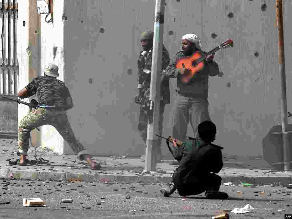 Liviyada keçid hökumətinin döyüşçüləri Muammar Qaddafinin doğulduğu Sirte şəhərində döyüşürlər, bu kişi isə gitarasından qalmır. (AFP PHOTO / ARIS MESSINIS)