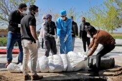 Люди в захисних масках та рукавицях на похованні жертви коронавірусу поблизу Тегерана (Іран). 30 березня 2020 року