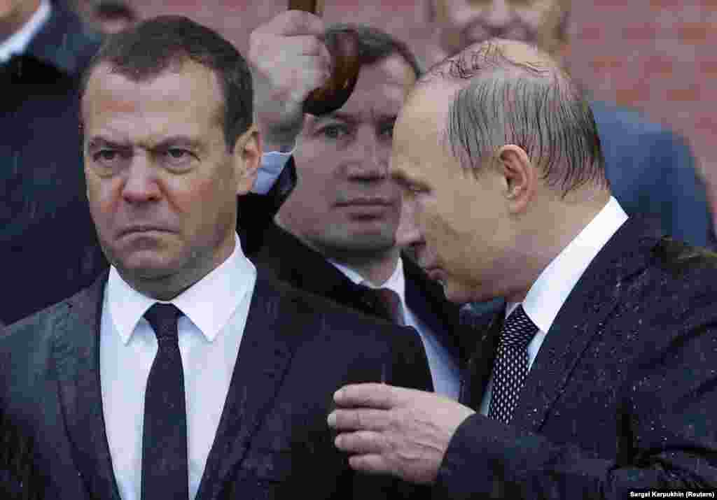Drenched by a downpour, Russian President Vladimir Putin (right) speaks with Prime Minister Dmitry Medvedev during a wreath-laying ceremony marking the anniversary of the Nazi invasion in 1941, by the Kremlin wall in Moscow on June 22. (Reuters/Sergei Karpukhin)