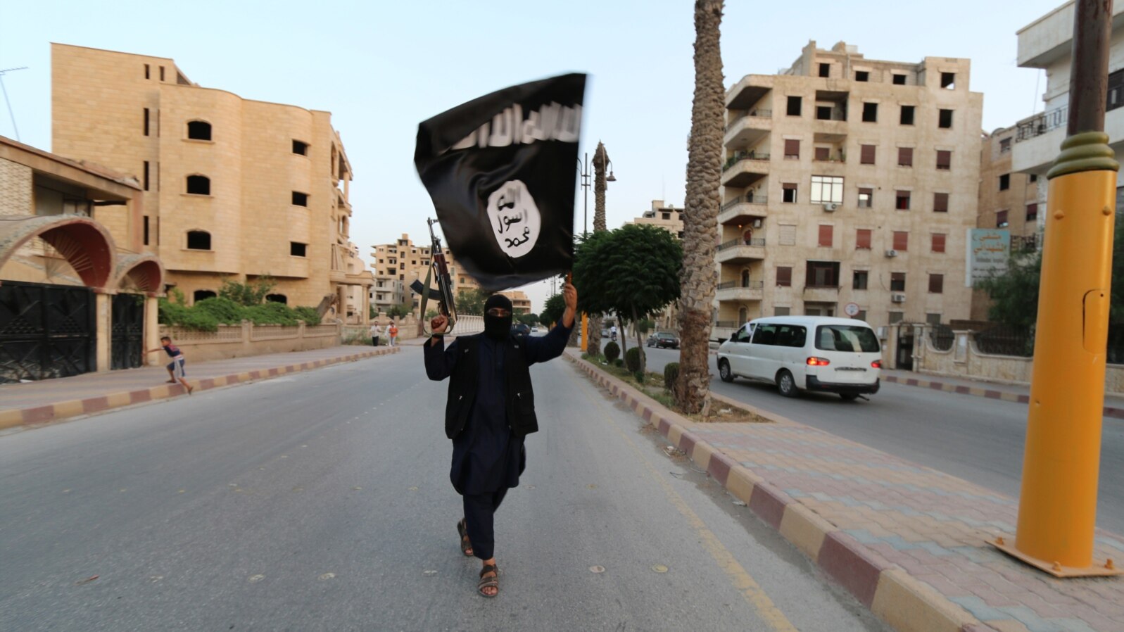 Un membru al militanților Statului Islamic flutură un steag în orașul sirian Raqqa.