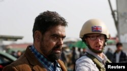 A British security official escorts a survivor from the wreckage of a British Embassy vehicle after a suicide attack in Kabul on November 27.