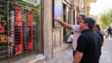People look at currency exchange rates displayed on an electronic board on the window of a shop in in Ferdowsi Square in the Iranian capital Tehran on September 28.