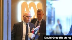 John Lyons, izvršni urednik autralijskog javnog kanala ABC News izlazi 5. juna iz glavne zgrade ABC-ja u Sidneju u pratnji saveznog policajca.