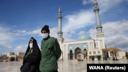 A couple wearing protective face masks following a coronavirus outbreak walk in the Iranian city of Qom. 