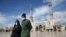 A couple wearing protective face masks following a coronavirus outbreak walk in the Iranian city of Qom. 
