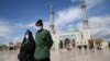 An Iranian couple wearing face masks to protect against the coronavirus walk in the holy city of Qom. 