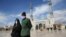 An Iranian couple wearing face masks to protect against the coronavirus walk in the holy city of Qom. 