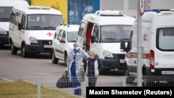 A medical specialist wearing protective gear accompanies a man outside a hospital for patients infected with the coronavirus disease on the outskirts of Moscow on October 7.