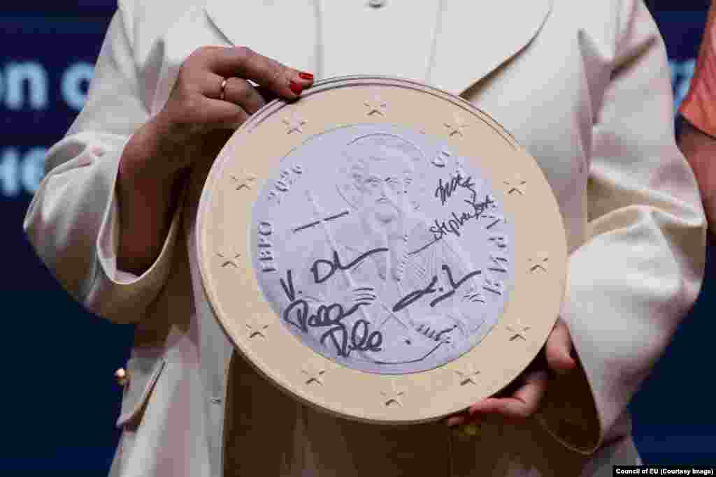 Žena drži model bugarskog novčića jednog evra tokom ceremonije EU povodom predstavljanja nove valute u julu.Na novčiću od jednog evra nalazi se Sveti Jovan Rilski, ličnost iz 9. veka po kome je nazvan Rilski manastir. Na bugarskom novčiću od dva evra biće ugravirana fraza "Bože, čuvaj Bugarsku".