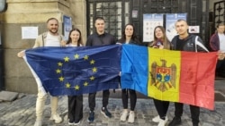 Moldovan citizens in Romania hold European and Moldovan flags at a diaspora polling site in Bucharest.