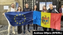 Cetățeni moldoveni din România țin steaguri europene și moldovenești la o secție de votare pentru diaspora din București, 28 septembrie 2025.