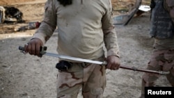 Иракский боец держит в руках саблю, подобную той, что джихадисты используют при обезглавливании пленных 