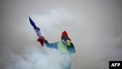 Участник протестов в Париже идет с французским флагом. 1 декабря 2018 года.