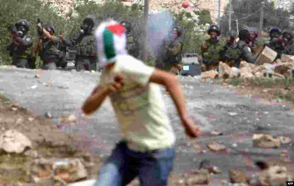 A Palestinian protester runs as Israeli soldiers fire tear gas during clashes at an April 13 demonstration against the expropriation of land by Israel in the village of Kfar Qaddum.