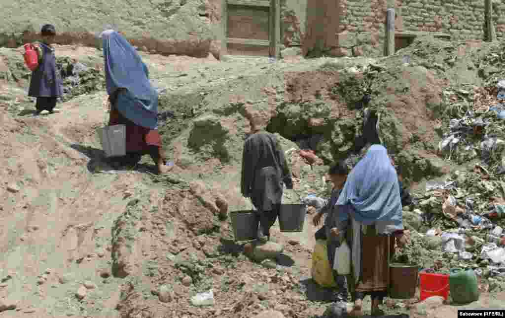 Women and children carry heavy buckets of drinking water. Many Kabul residents don't have access to clean water in or near their homes.